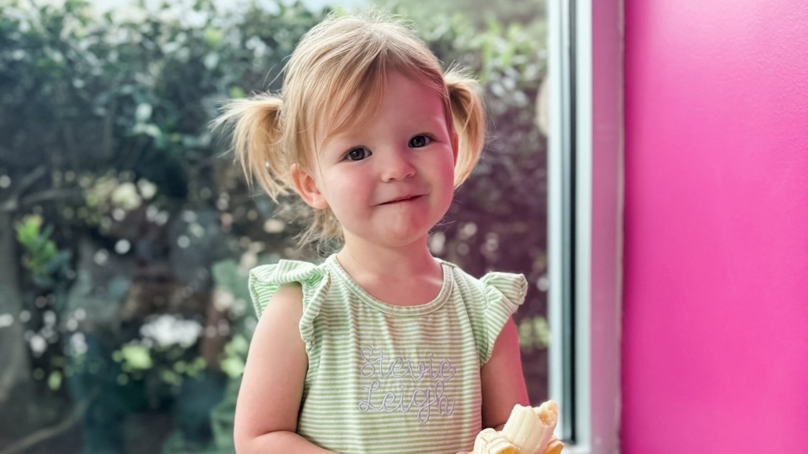 Calm, smiling toddler holding a banana, a picture of emotional regulation in kids